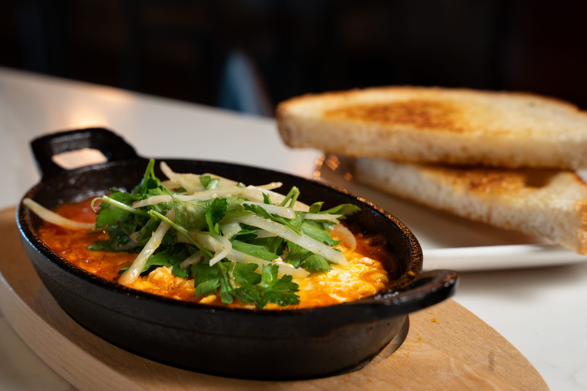 Baked eggs with fresh herbs in a cast-iron skillet, served with toast